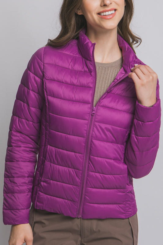 Woman wearing a purple puffer jacket on a gray background