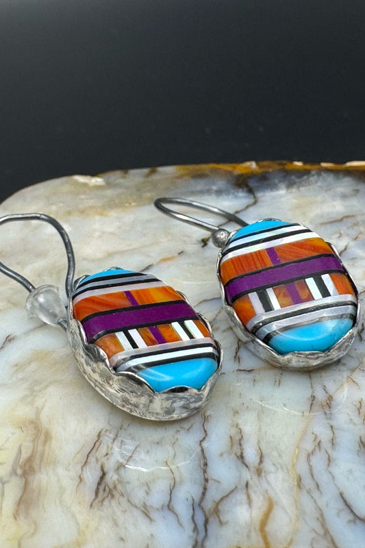 Multicolored striped earrings on a marbled stone surface