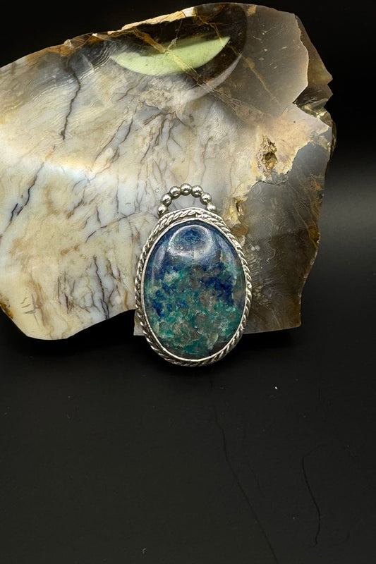 Silver pendant with a blue stone on a piece of marble