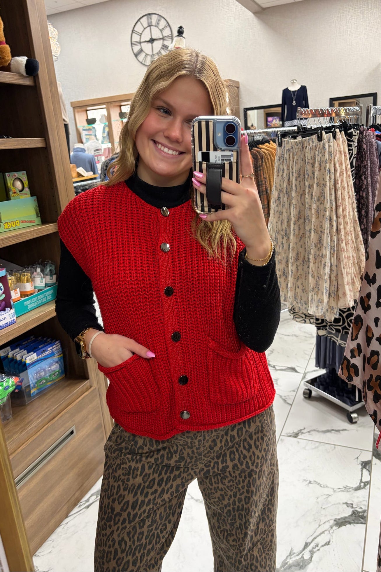 Person wearing a red cardigan and leopard print pants in a store