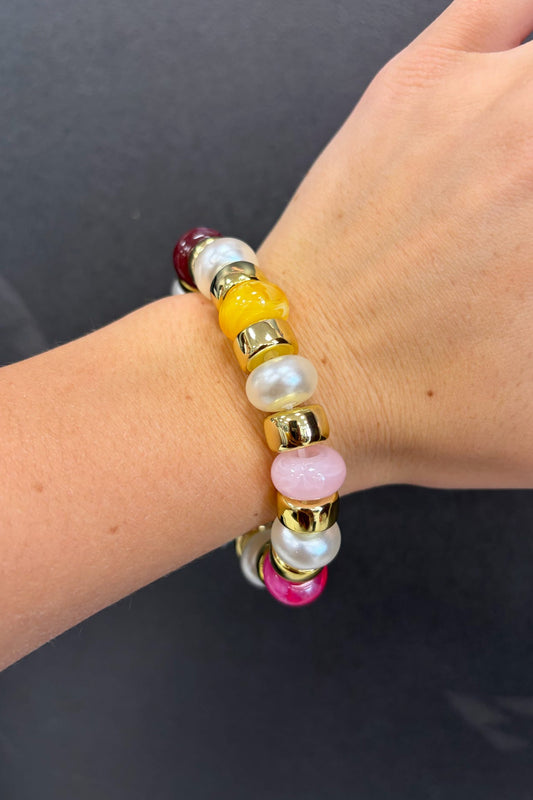 Multicolored beaded bracelet on a wrist against a dark background