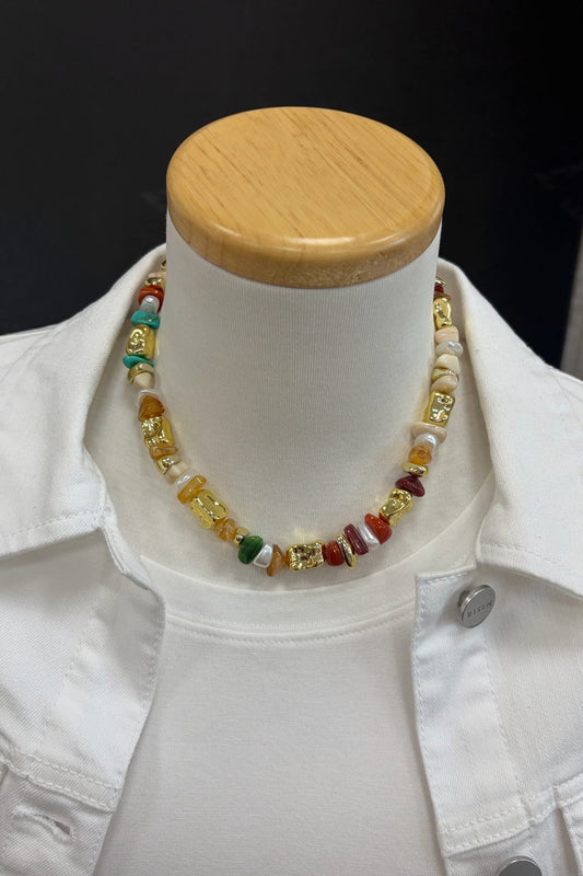 Colorful beaded necklace on a mannequin bust with a white jacket.