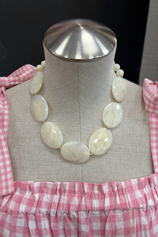 Necklace on a mannequin with pink checkered dress
