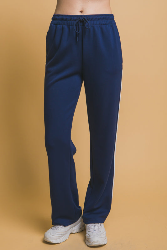 Blue sweatpants worn by a person on a beige background