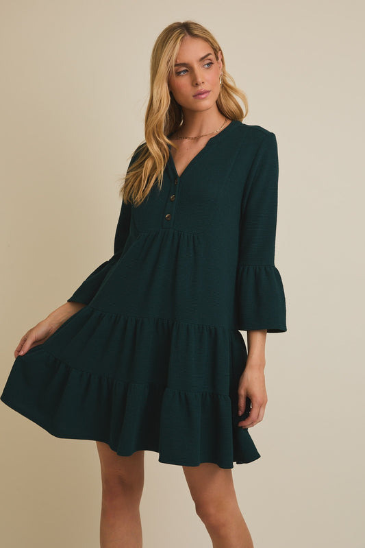 Woman wearing a dark green dress with long sleeves on a beige background