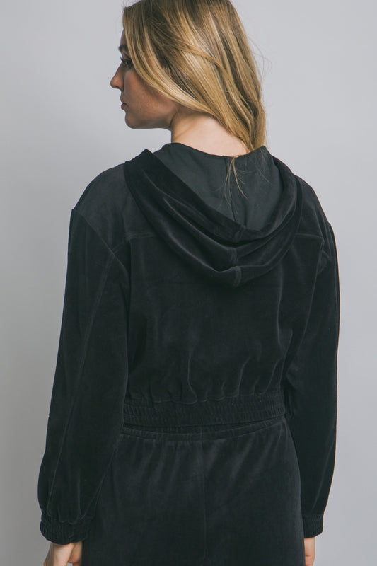 Person wearing a black hoodie against a plain background