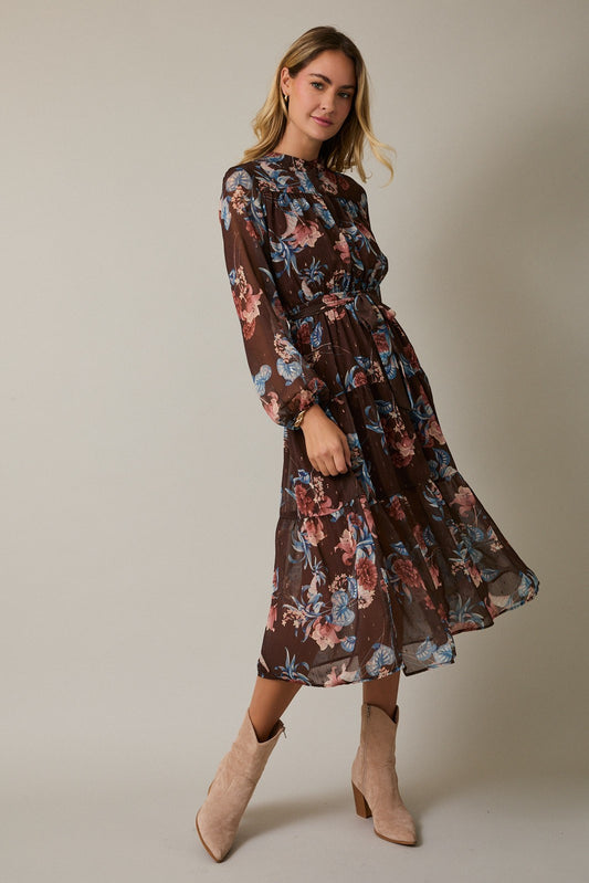Woman wearing a floral dress with long sleeves on a plain background