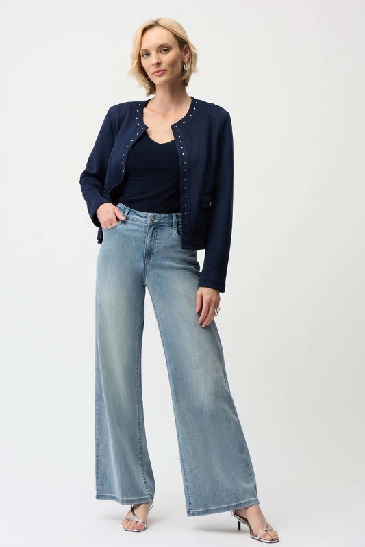 Woman wearing a navy cardigan, black top, and light blue jeans on a white background