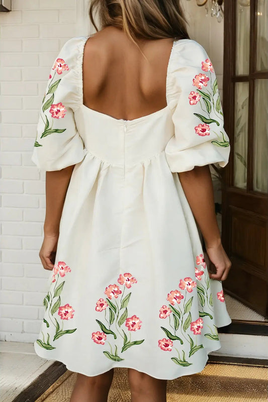 White dress with floral embroidery on a person standing indoors.