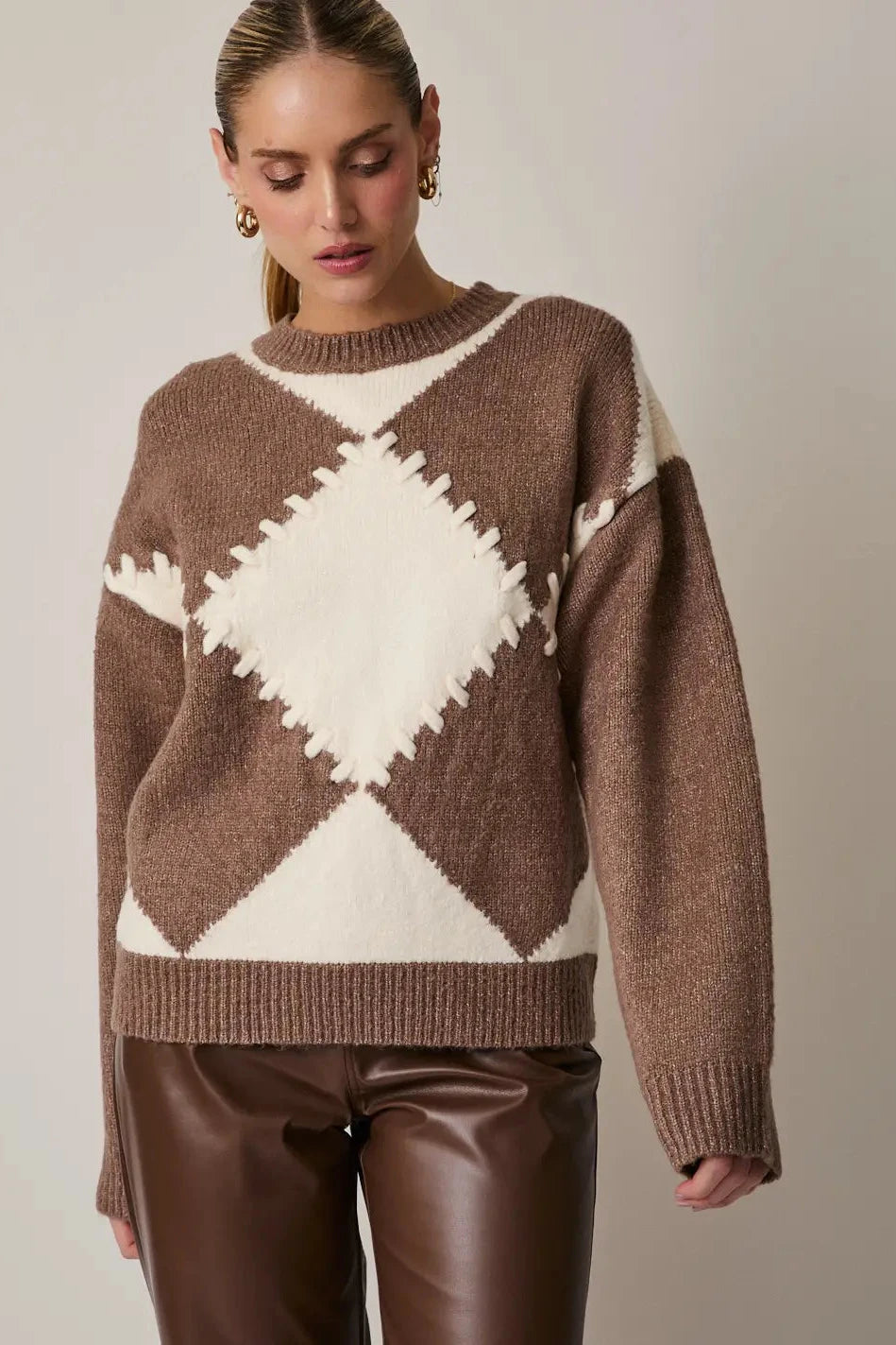 Woman wearing a brown and white patterned sweater against a plain background