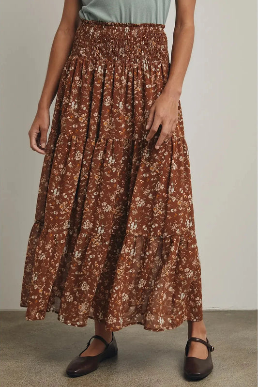 Person wearing a brown floral skirt with a plain background