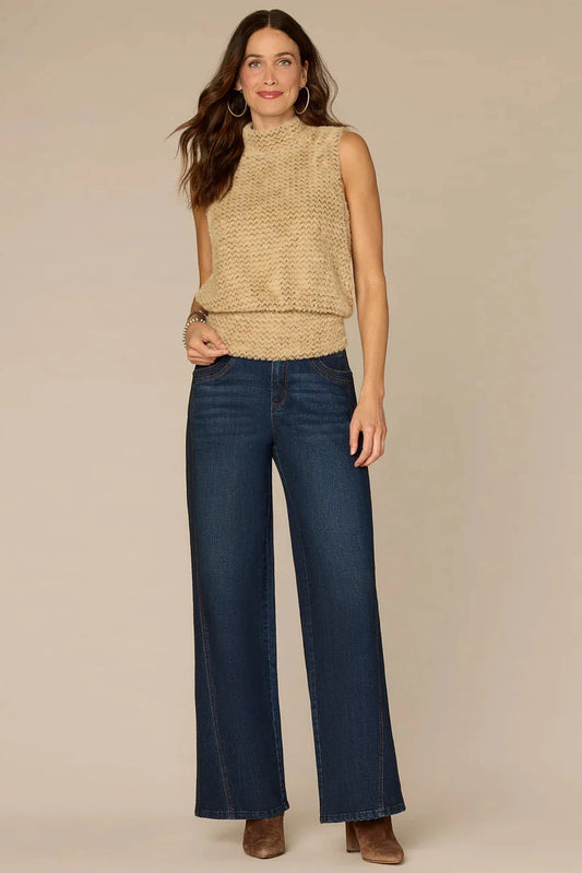 Woman wearing a beige sleeveless top and blue jeans on a beige background