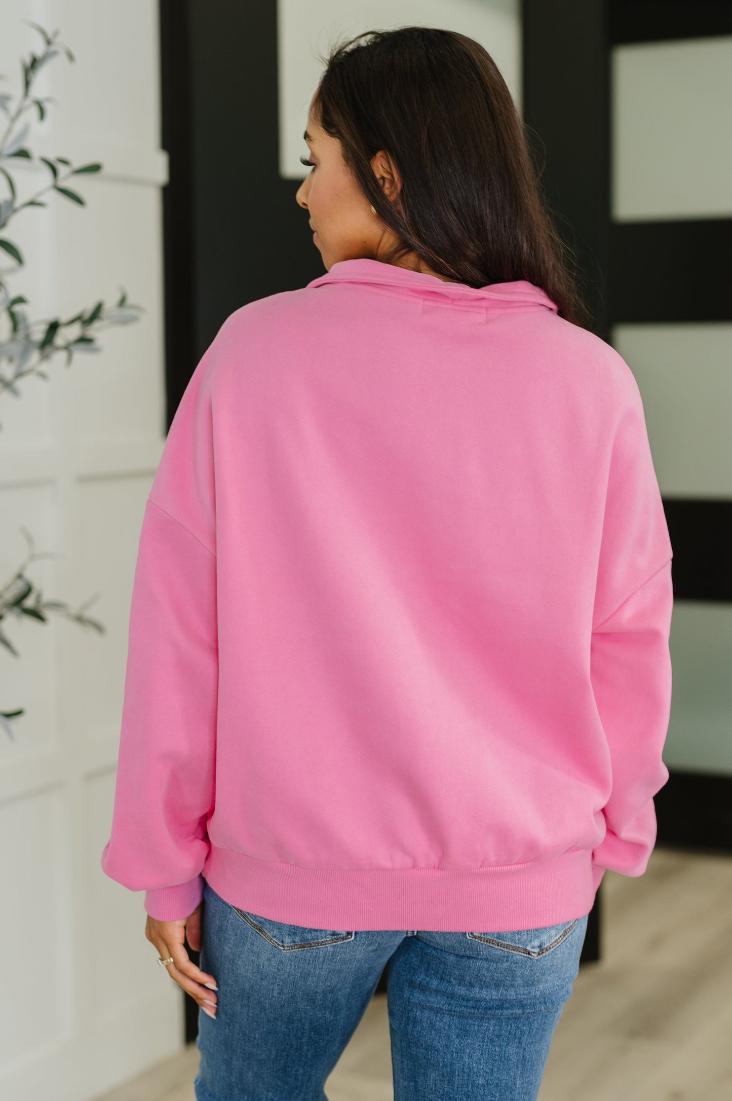 Person wearing a pink sweatshirt and blue jeans in an indoor setting