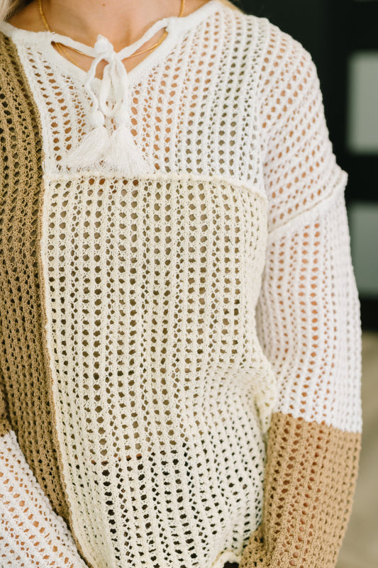 Close-up of a person wearing a beige and white crochet top with a blurred background