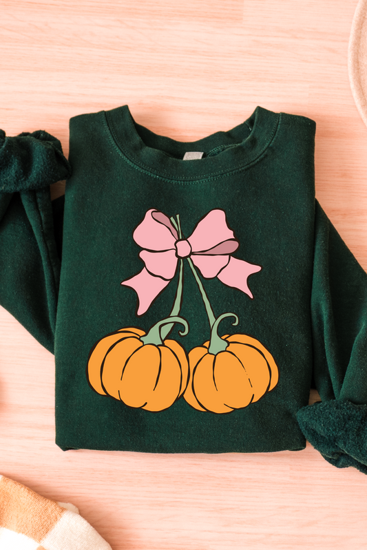 Green sweatshirt with pumpkin and bow design on a wooden surface