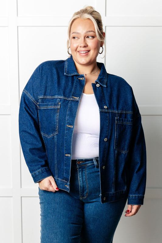 Person wearing a blue denim jacket and jeans against a white background