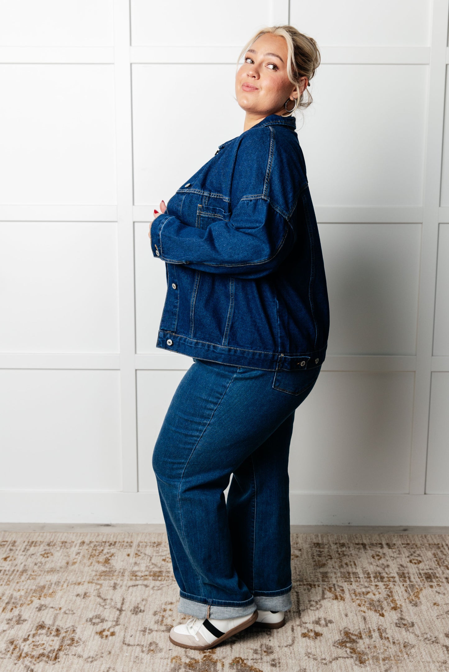 Person wearing a blue denim outfit standing against a white tiled wall.