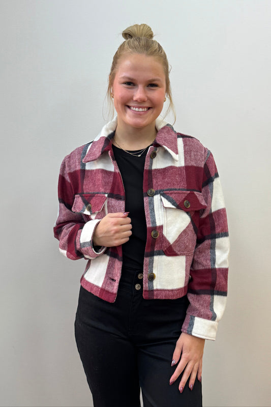 Person wearing a plaid jacket on a plain background