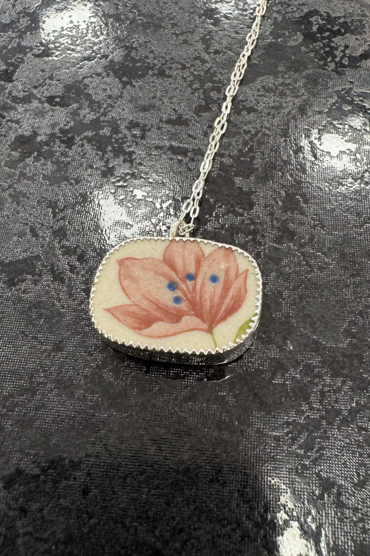 Necklace with a floral pendant on a reflective surface