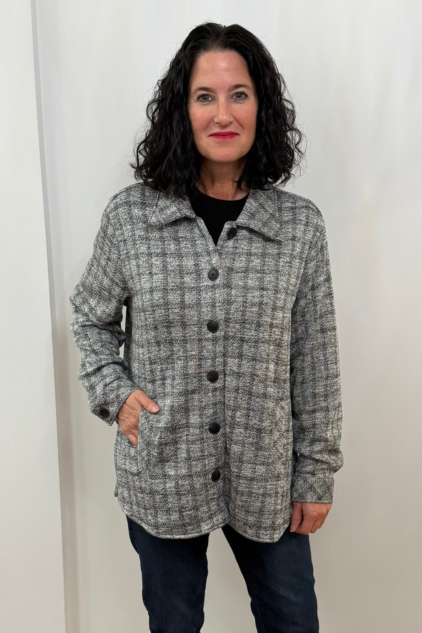 Woman wearing a checkered coat standing against a white curtain