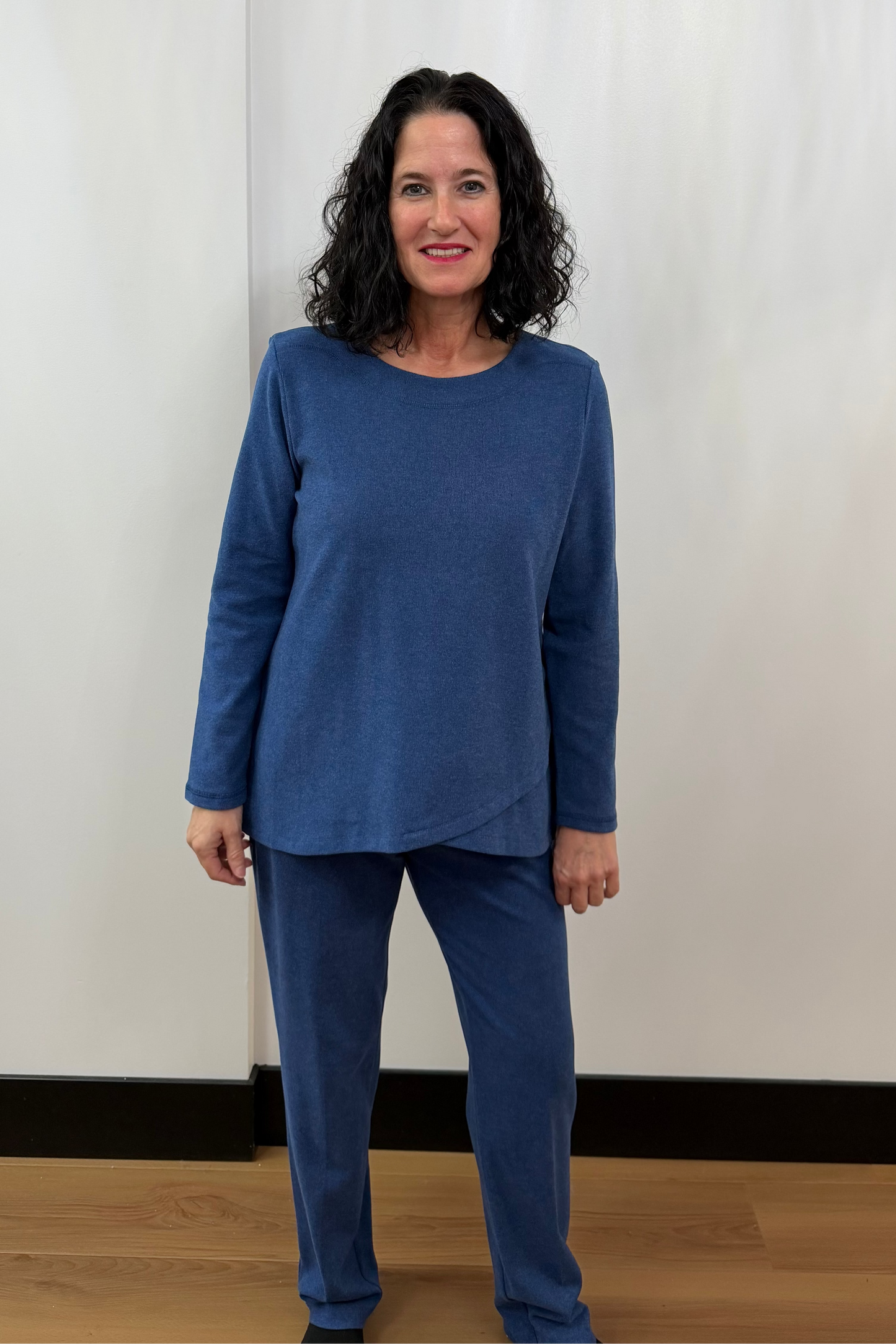 Woman wearing a blue outfit standing against a white curtain background