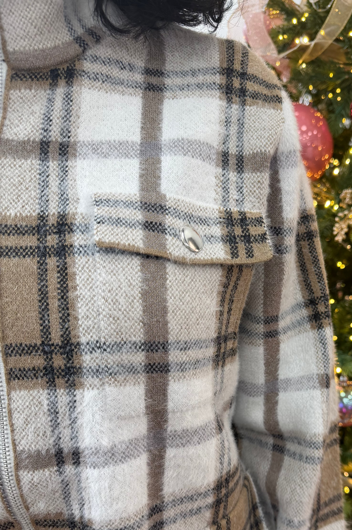 Plaid coat with a Christmas tree decorated with ornaments in the background