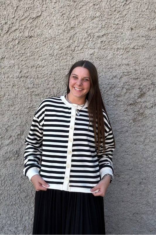 Woman wearing a black and white striped sweater against a textured wall.