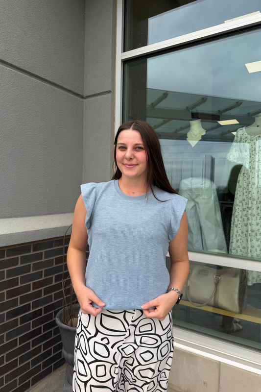 Woman standing outside a store with a window display in the background
