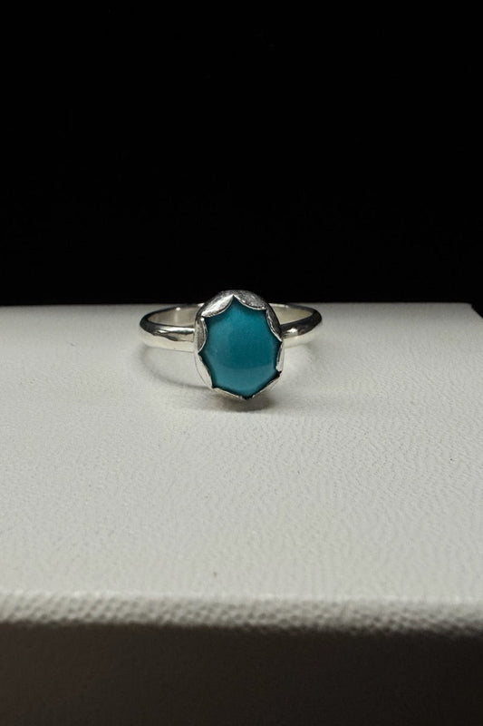 Silver ring with a blue gemstone on a white surface