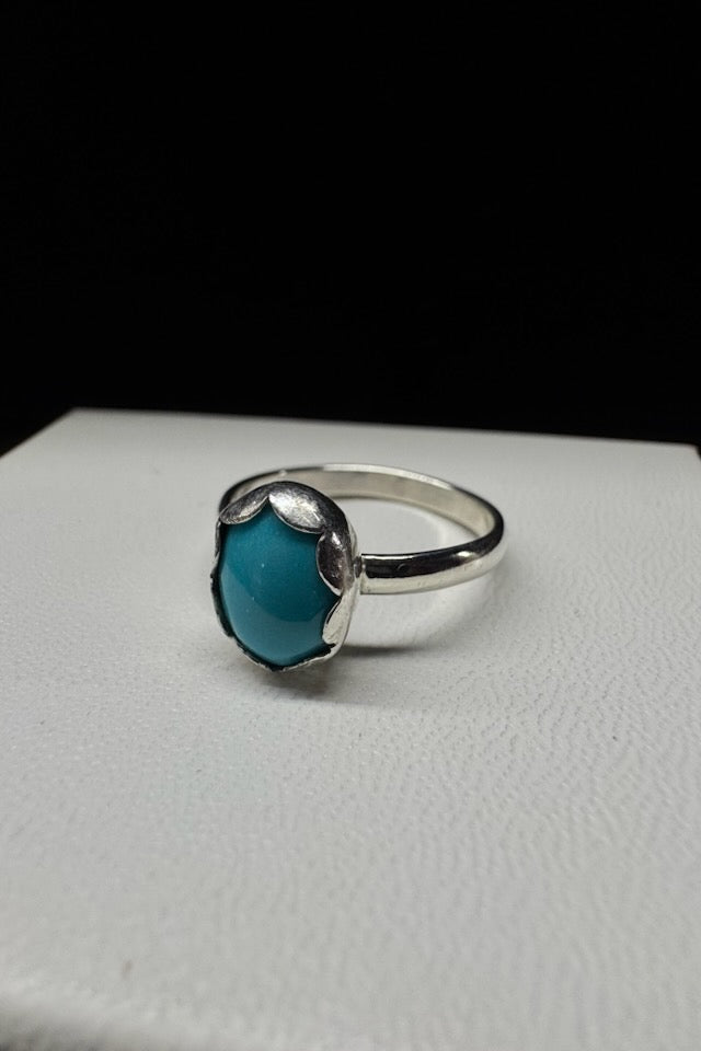Silver ring with a blue stone on a white surface