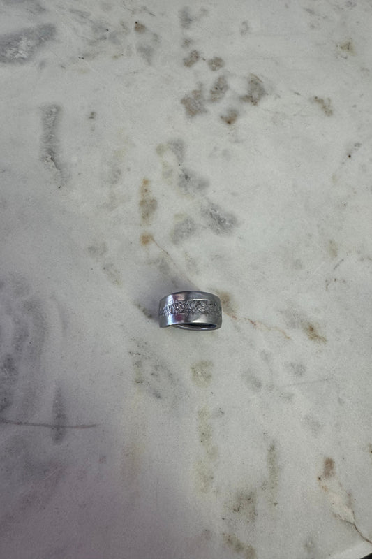 Silver ring with floral designs on a marble surface