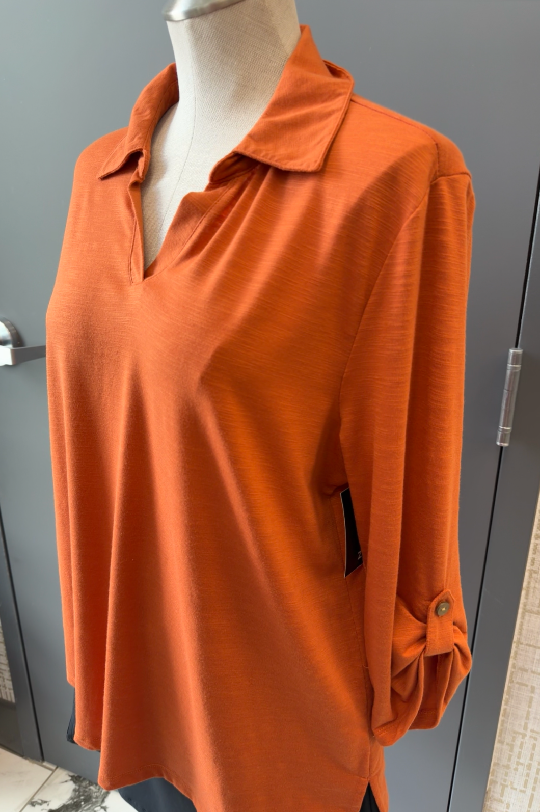 Orange blouse on a mannequin against a gray background