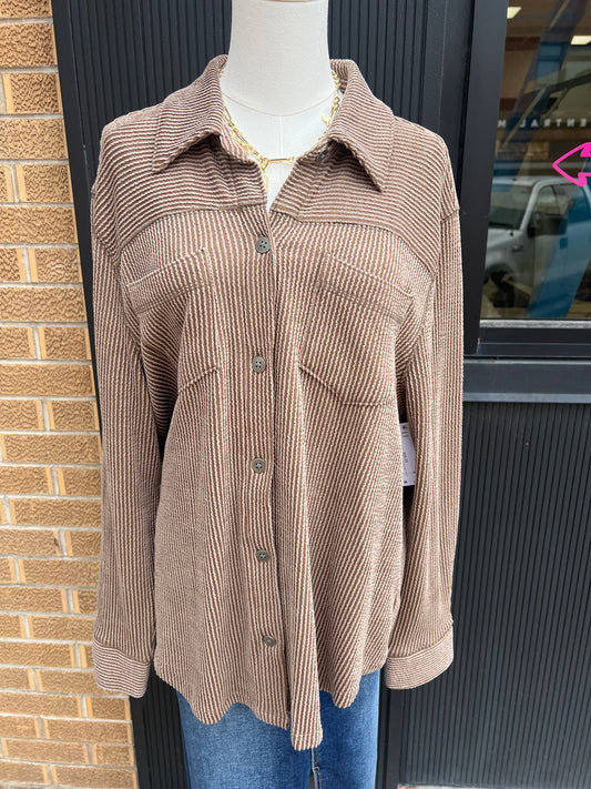 Brown corduroy shirt on a mannequin against a brick wall.