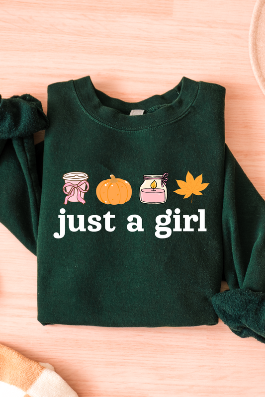 Green sweatshirt with 'just a girl' text and icons on a wooden surface