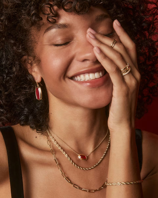 Woman wearing gold jewelry with a red background