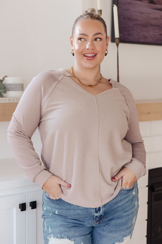 Woman wearing a beige sweater and blue jeans indoors