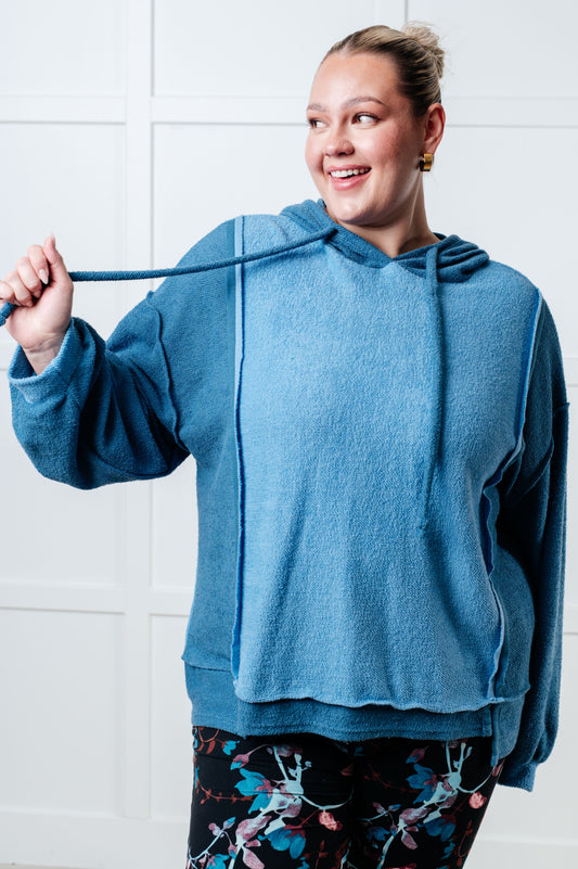 Person wearing a blue hoodie with a white tiled wall background