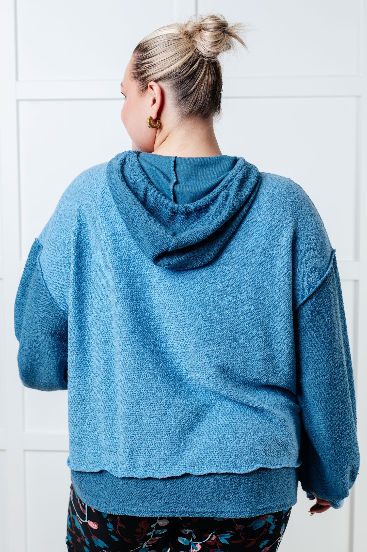 Person wearing a blue hoodie with a white tiled wall background