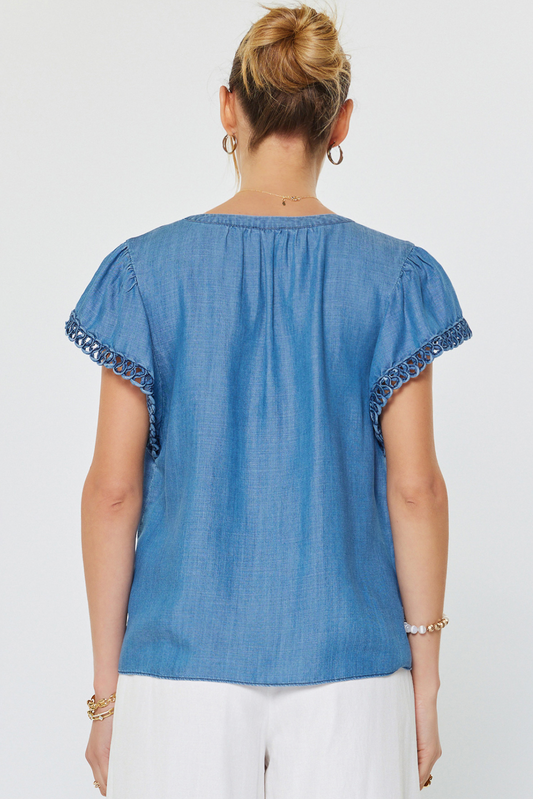 Woman wearing a blue top with decorative sleeves on a white background