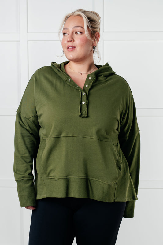 Woman wearing an olive green hoodie against a white background