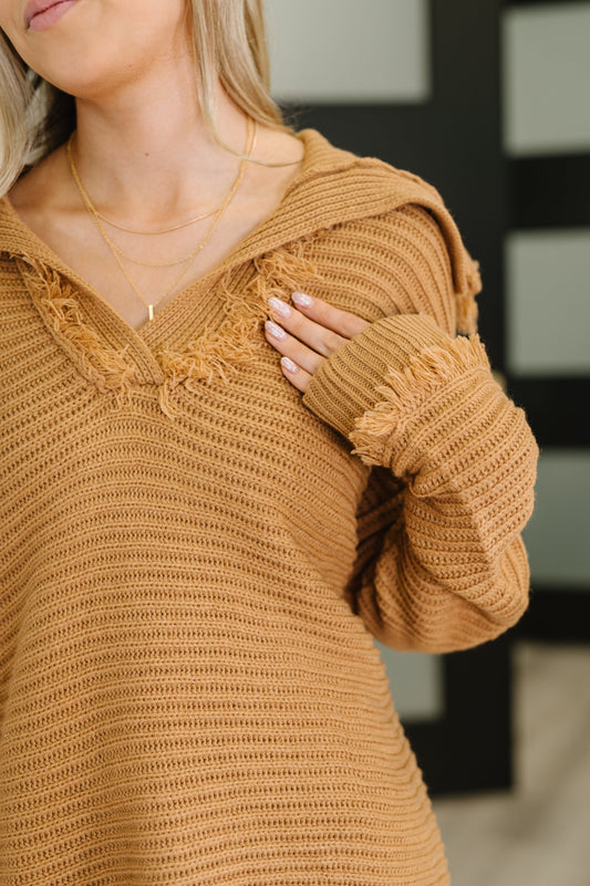 Close-up of a person wearing a brown knitted sweater with a blurred background