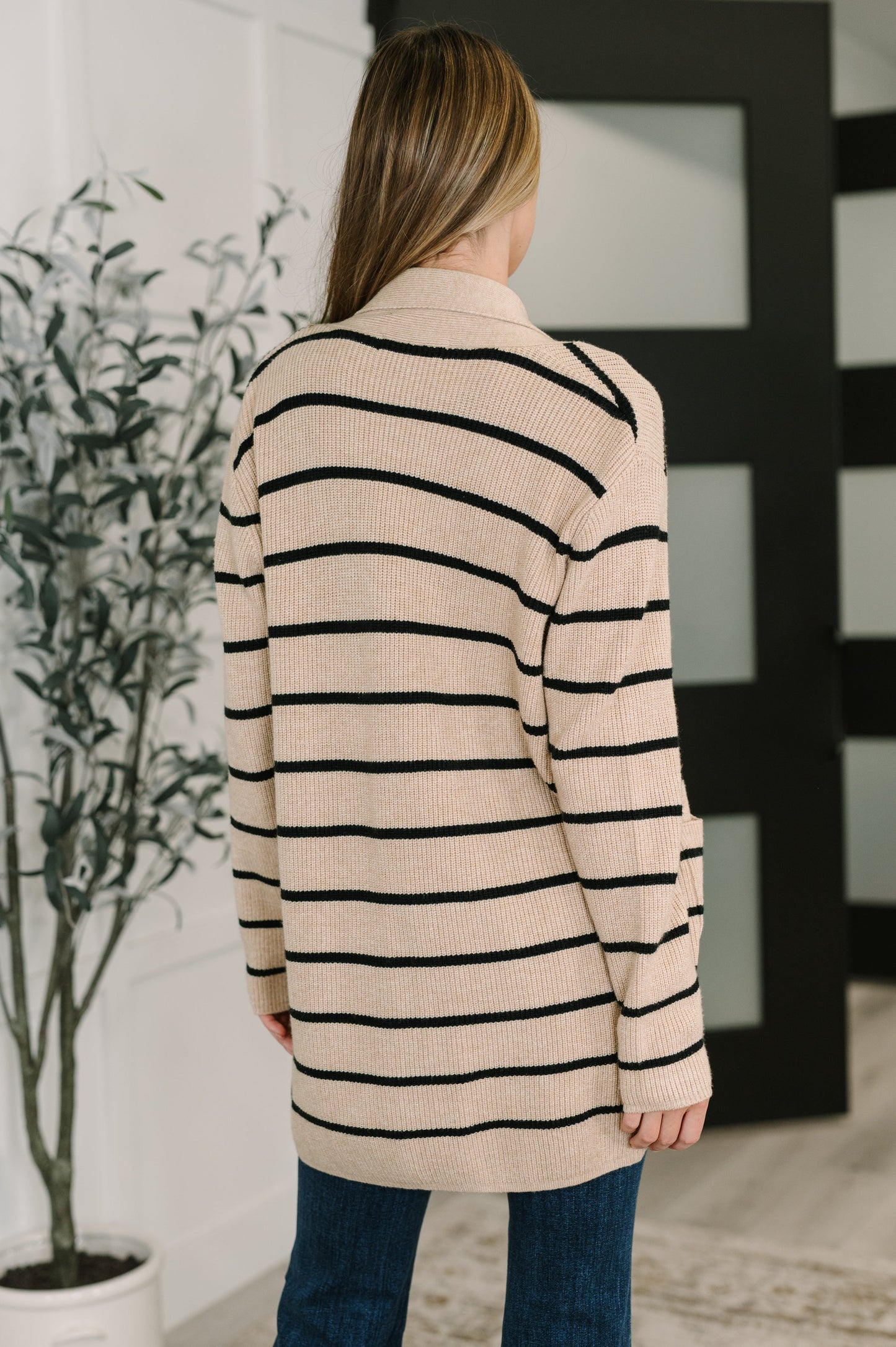 Person wearing a beige and black striped sweater in an indoor setting.