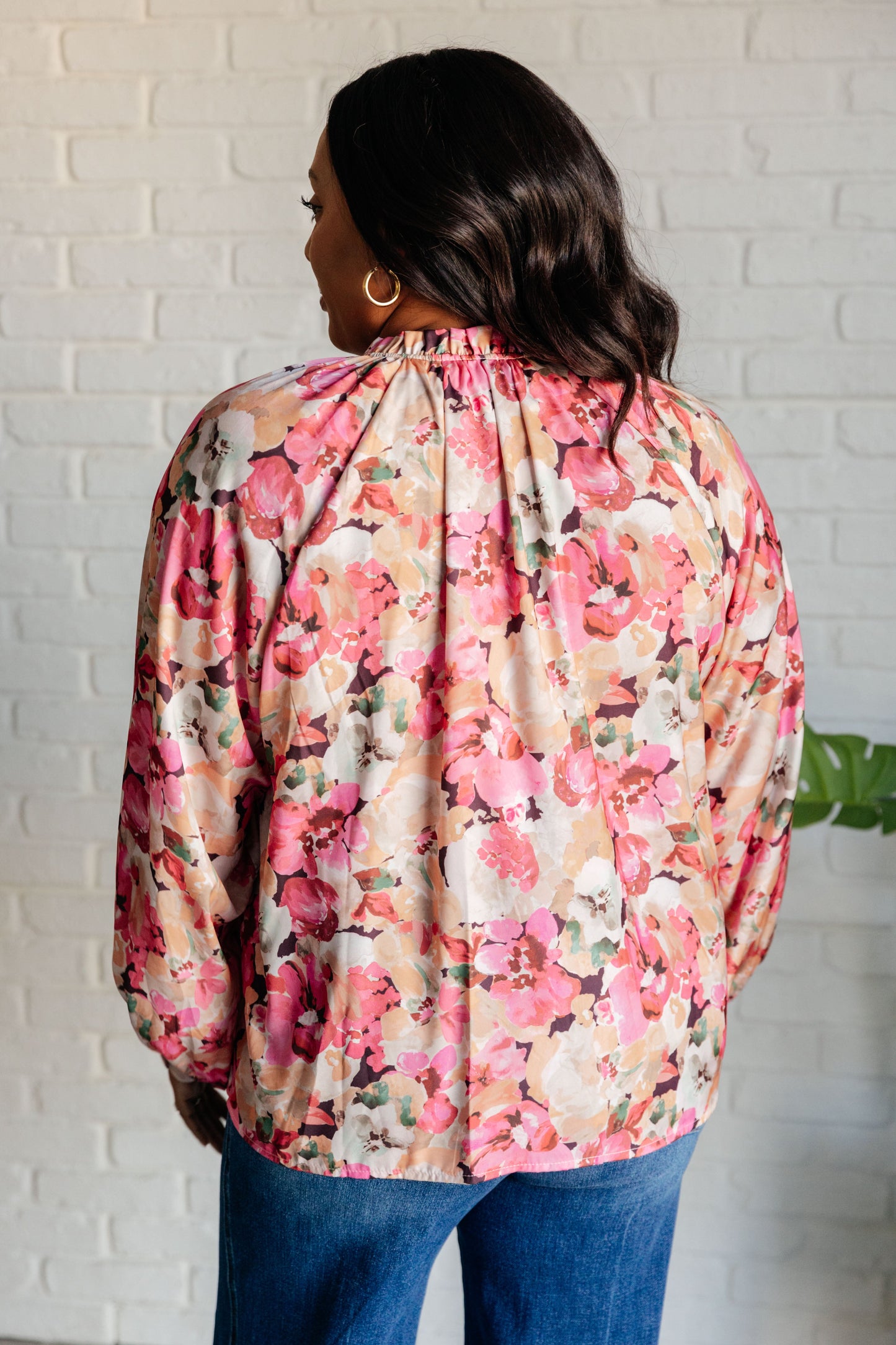 Person wearing a floral blouse with a white brick wall background