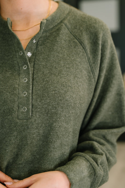 Close-up of a person wearing a green long-sleeve shirt with buttons.