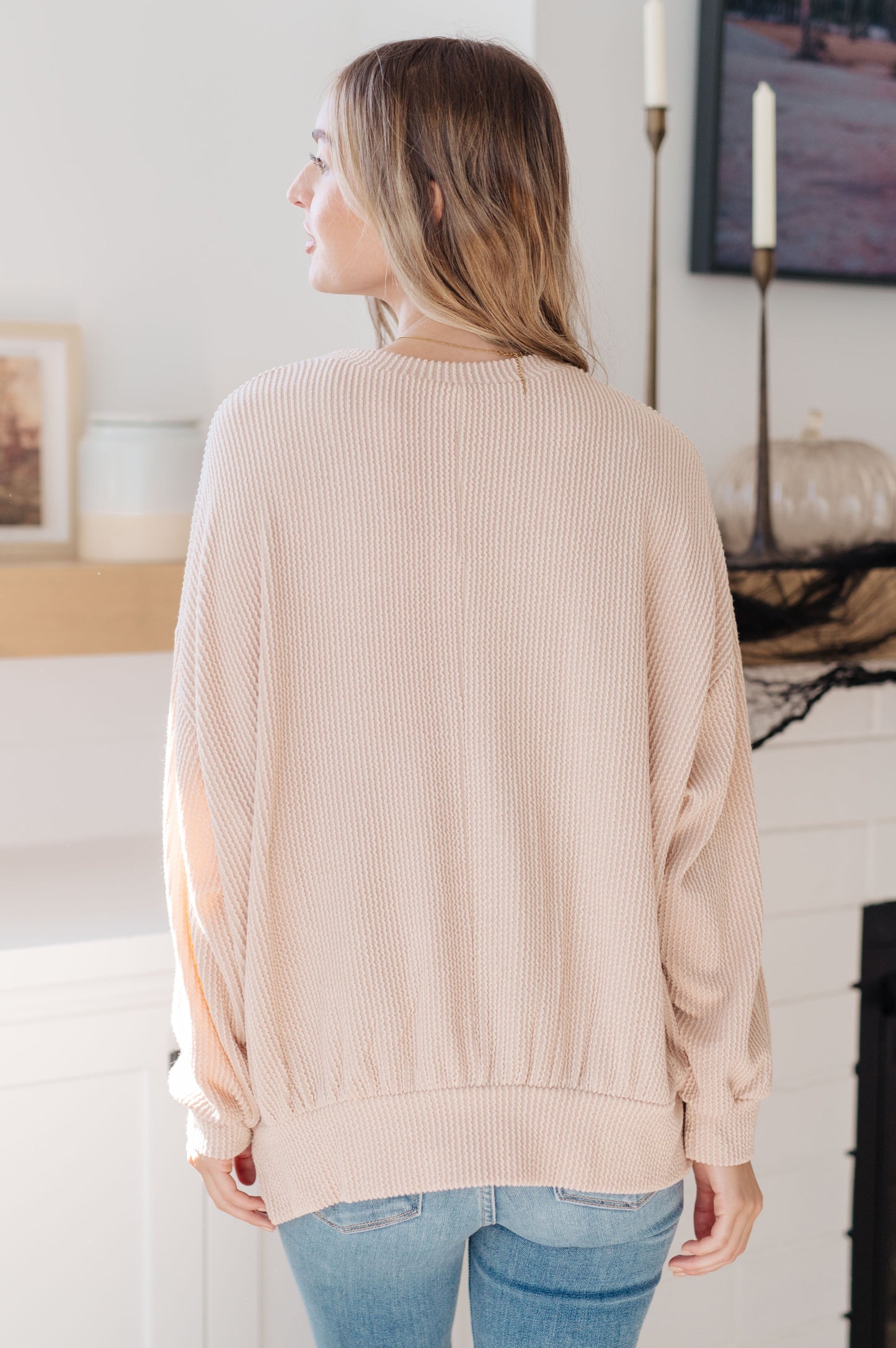 Woman wearing a beige sweater in a living room setting