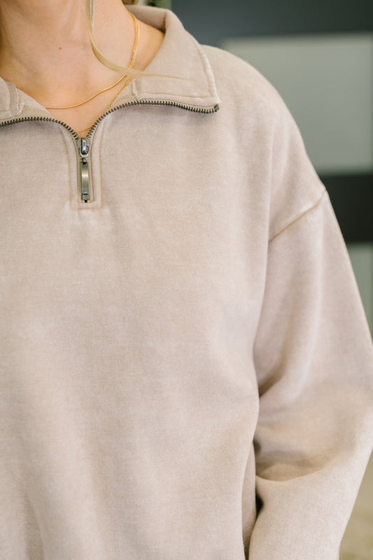 Close-up of a beige pullover with a quarter zip.