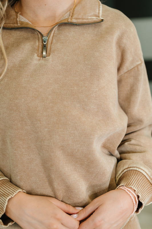 Close-up of a person wearing a beige sweater with a zipper.