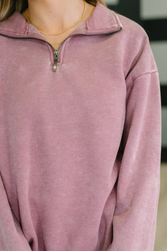 Close-up of a person wearing a pink pullover with a zipper.