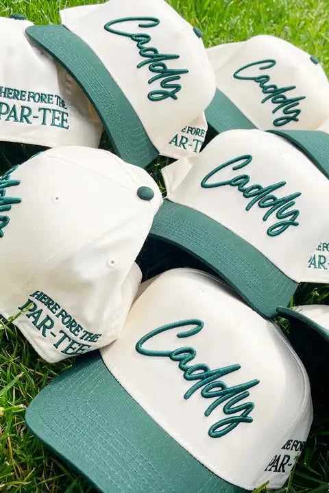 White caps with green accents and 'Caddies' text on grass