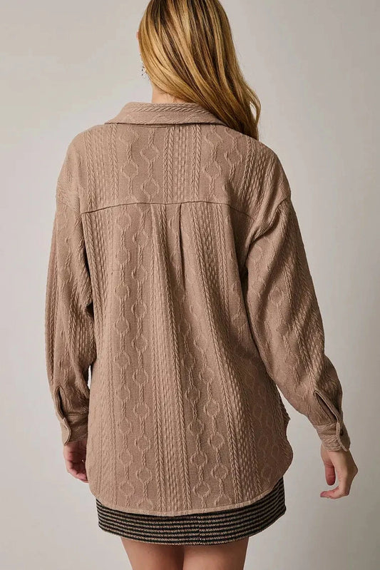 Person wearing a beige textured jacket against a plain background